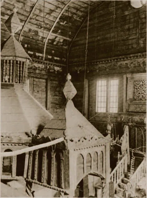 Sepia interior photograph looking up at the pointed canopy of the bimah and a stair rail, with the wooden barrel vault and a window beyond.