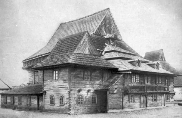 Black-and-white photograph of the synagogue from a corner, showing the high main roof, dormers and a galleried annex.
