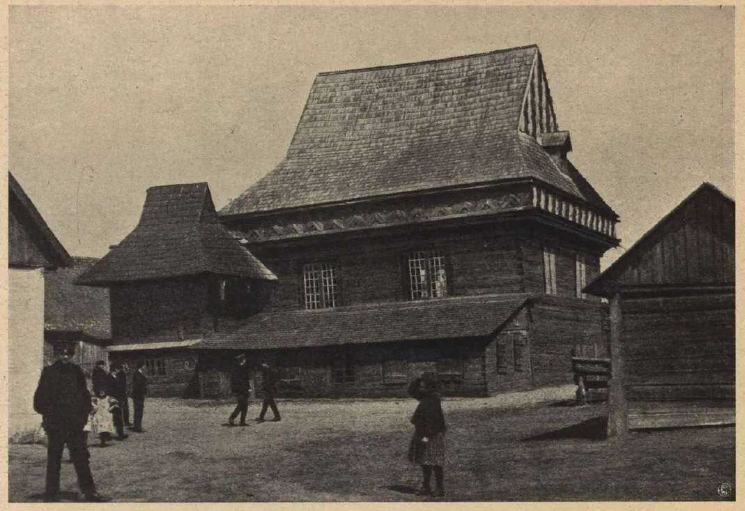 Sepia photograph of the synagogue across an open square with several pedestrians, the tiered roofs and side pavilions clearly visible.