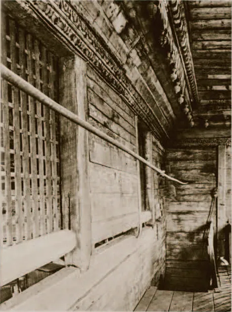 Sepia photograph of tall latticed wooden screens and plank walls under a carved cornice, a narrow wooden passage beside them.